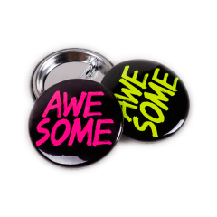 Neonknappar - svarta reklamknappar med text i gul och cerise neonfärg. Fästet med nål syns också på bilden